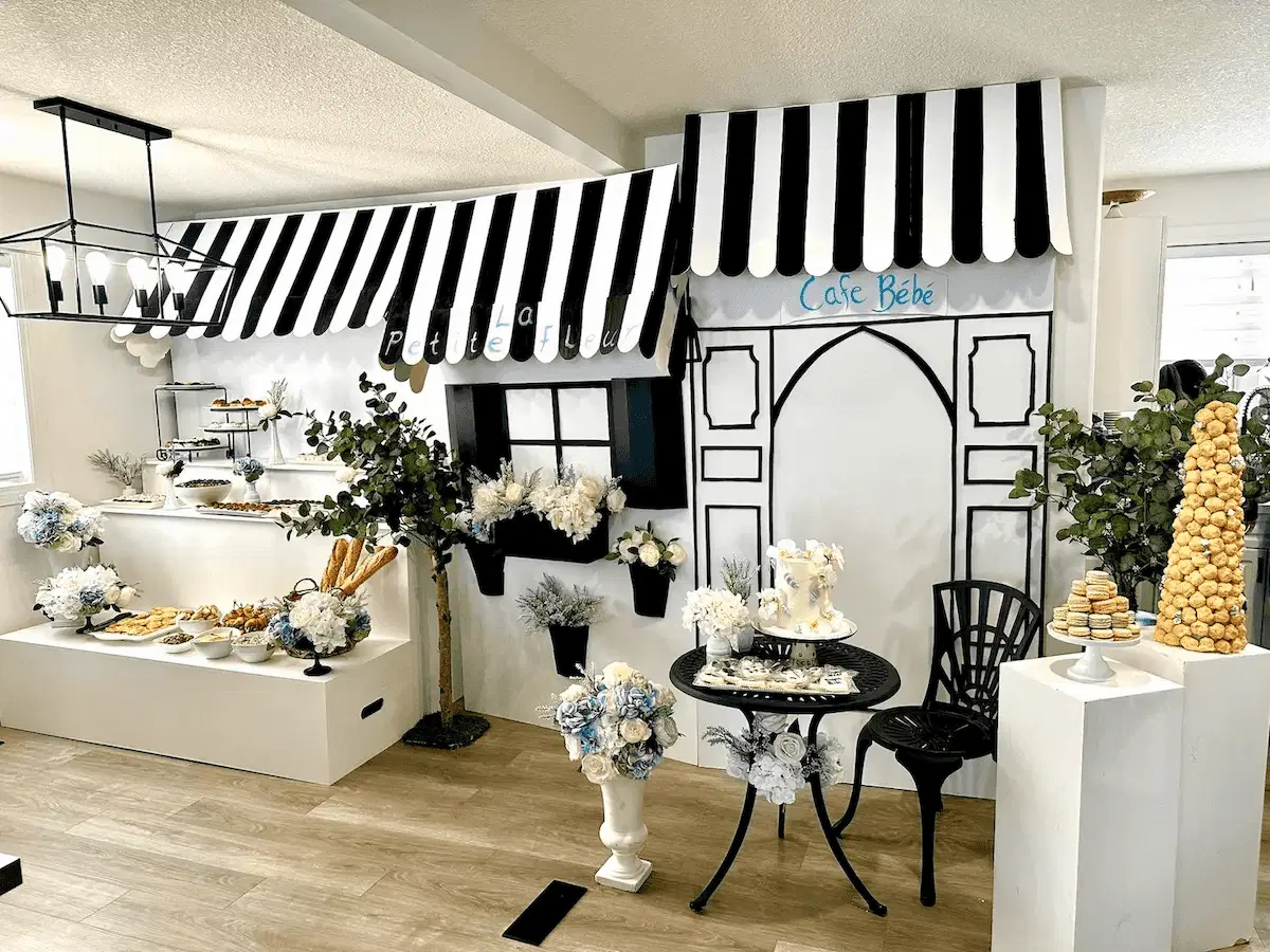 Ornate event backdrop featuring a curved ivory chaise lounge, draped white curtains, cascading white floral arrangements while being enviornmental friendly, and delicate glass votive candle accents, perfect for a wedding or special occasion.